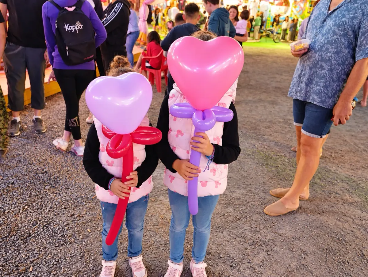 Deux enfants tenant des cœurs sculptés en ballons lors d'une fête