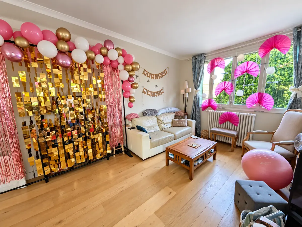 Arche de ballons et mur de sequins dorés installés dans un salon pour une fête
